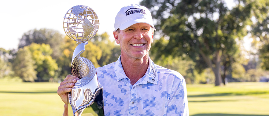 2023 International champion smiling and holding his trophy outside on the golf course