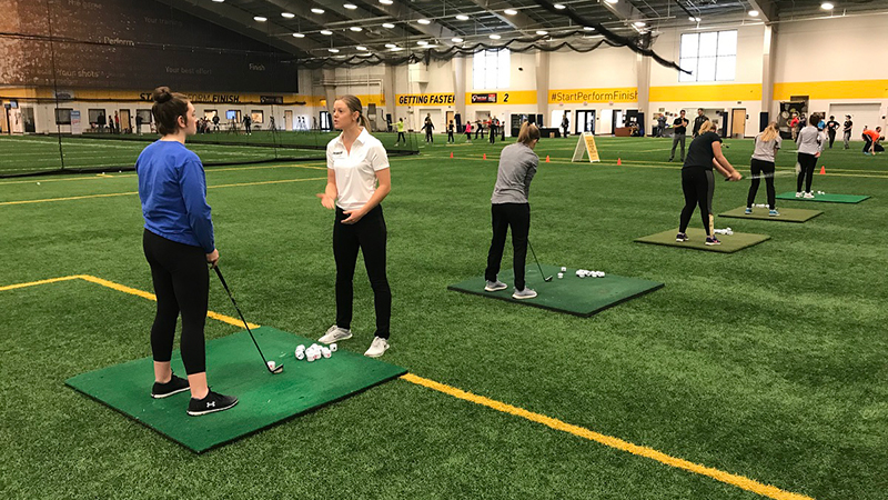 players practicing golf inside Sanford Fieldhouse