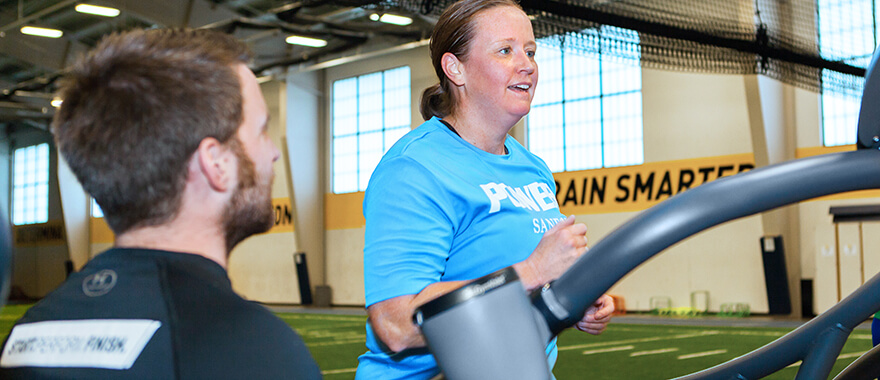 Athlete running on a treadmill while being coached by a Sanford Sports Performance trainer
