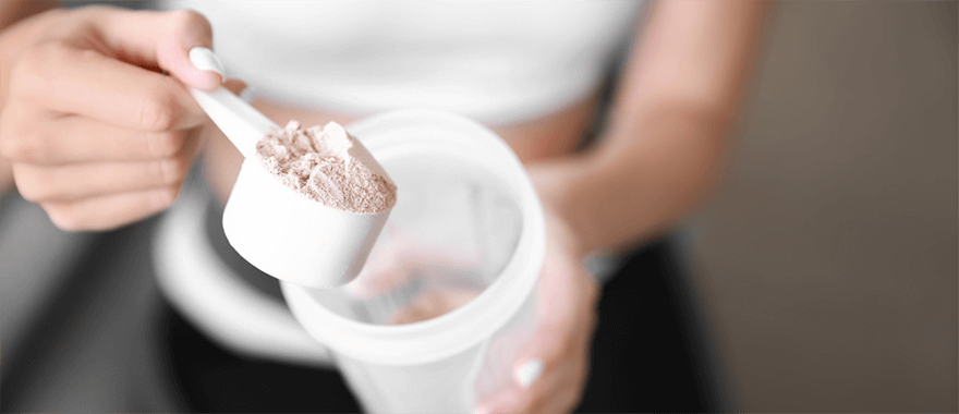 image of female dumping protein powder into her shaker bottle