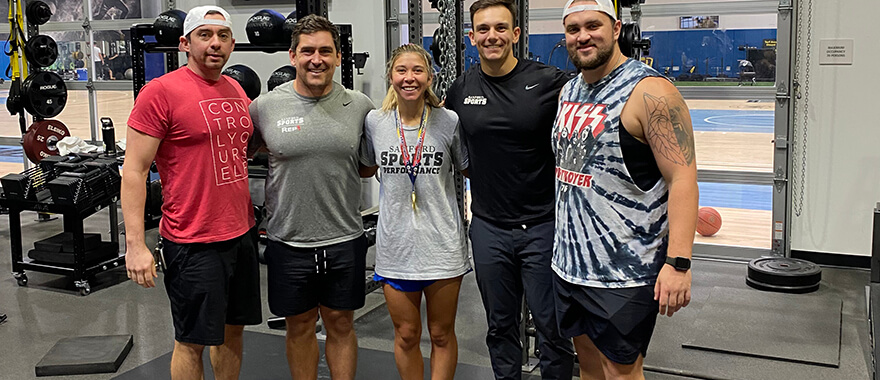 US Women's Dead National Team member Emily Spreeman pictured wearing her gold medal while standing next to her Sanford Sports Performance trainers