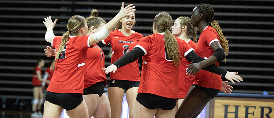 sanford sports academy volleyball team celebrates on the court during a match