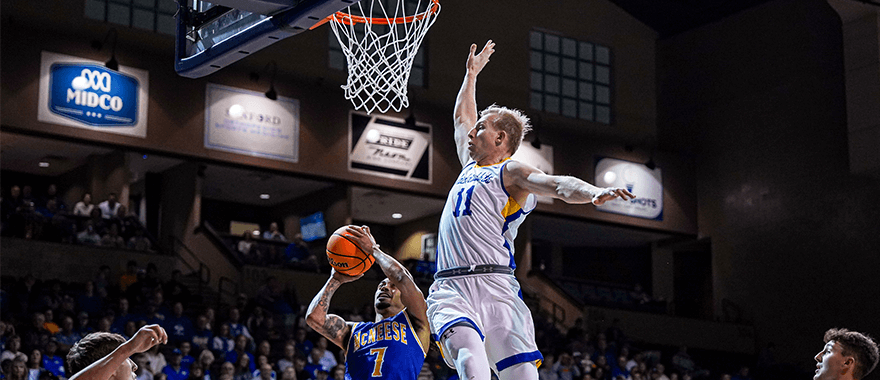 SDSU men's basketball player goes up to block shot during game at the Sanford Pentagon