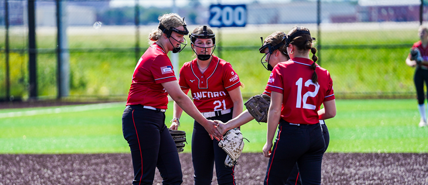 Softball players meeting at the mound