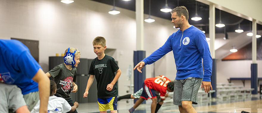 Logan Storely coaching a wrestler at his camp at the Sanford Pentagon