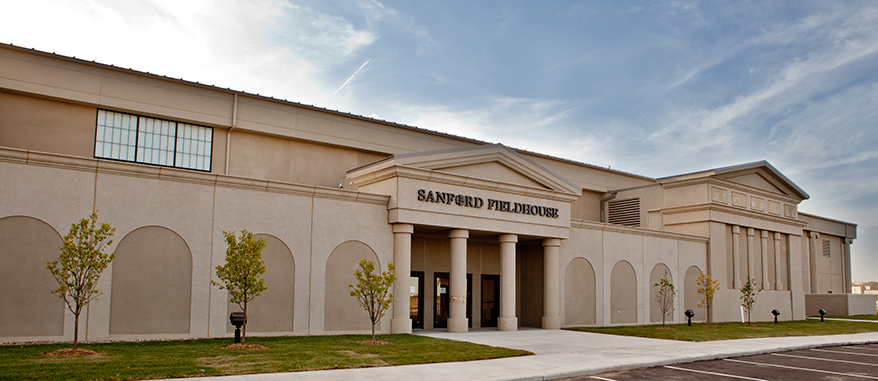 exterior of the Sanford Fieldhouse with green grass and blue skies
