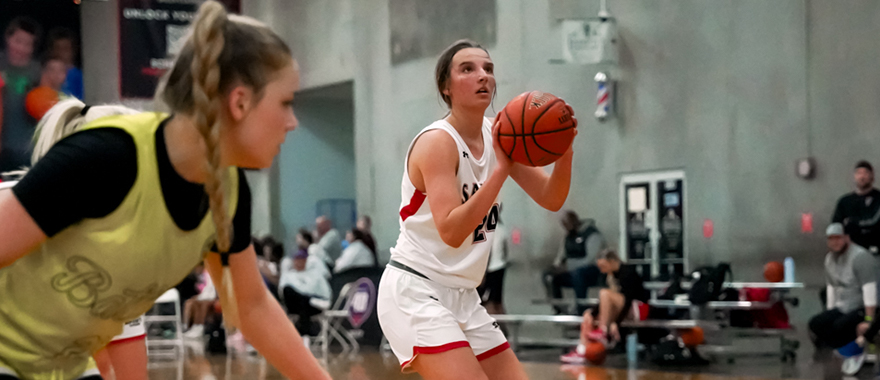 Girl shooting a basketball with an opponent approaching