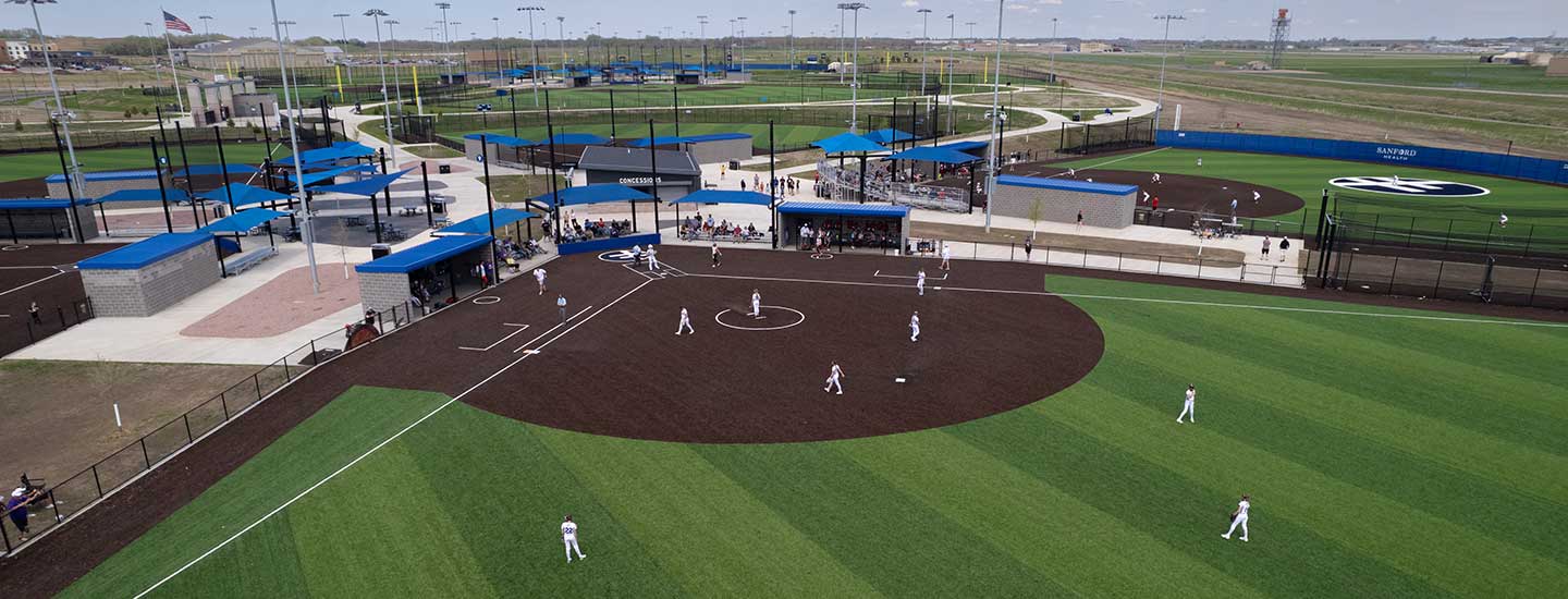exterior drone shot of sanford diamond baseball field facing home base, with players on the field