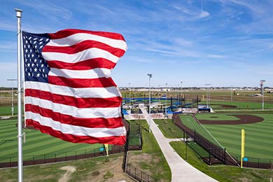 drone photo of sanford baseball diamonds with the american flag waving close up