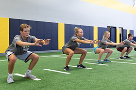 athletes doing squats in performance training