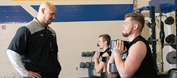coach training high school athletes in weight room