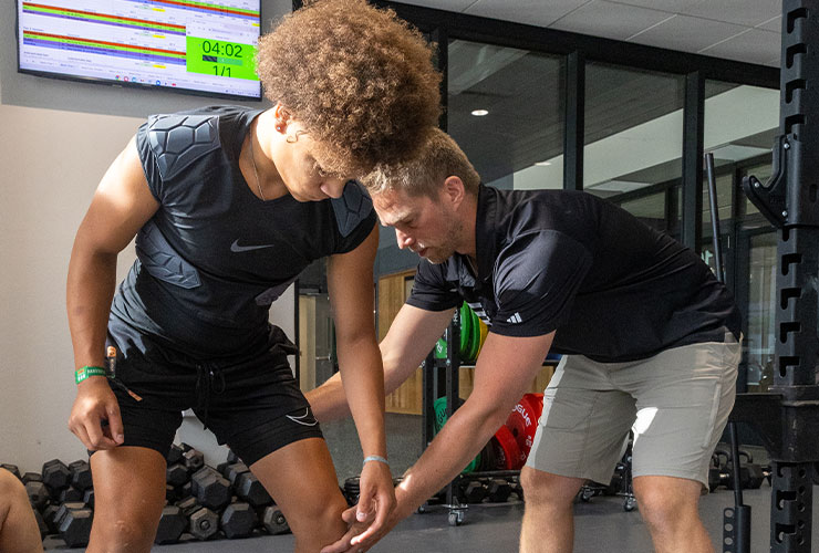 Player weight training in room with coach