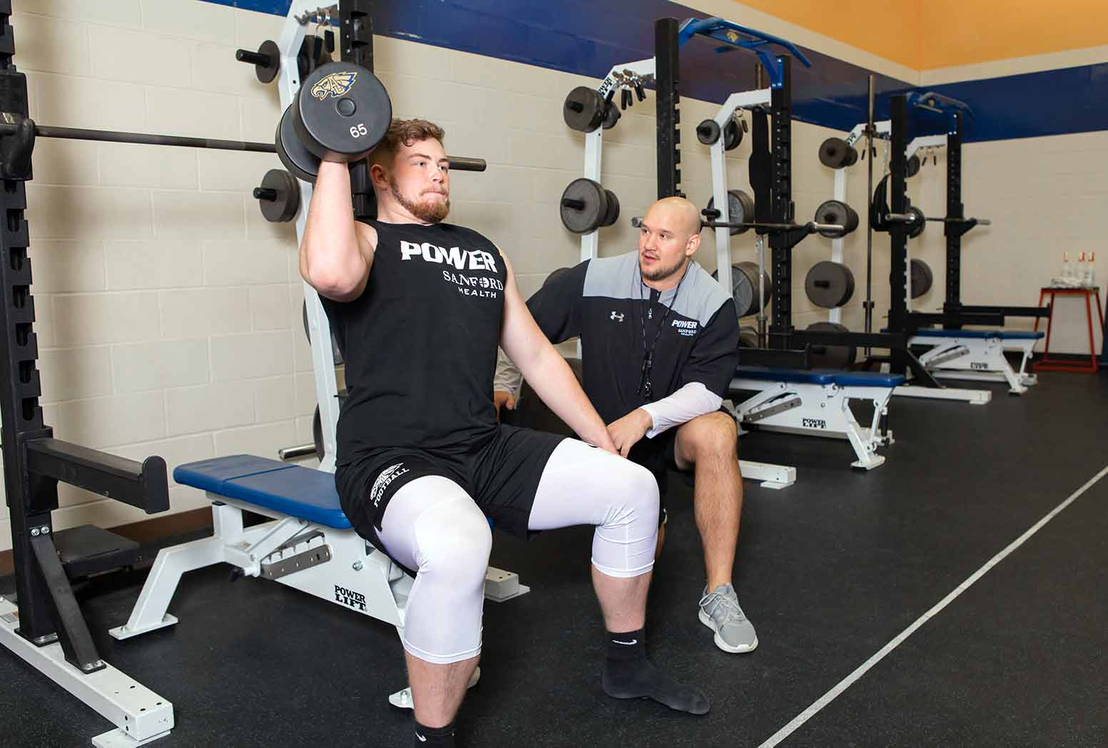 Player weight training in room with coach