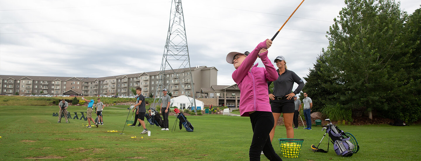 golfer practicing at driving range with Sanford coach