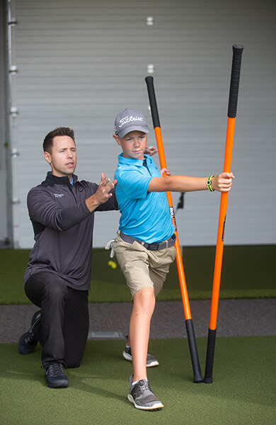 golf coach assisting youth golfer in performance training
