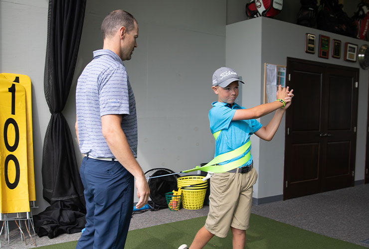 Golf instructor teaching young boy