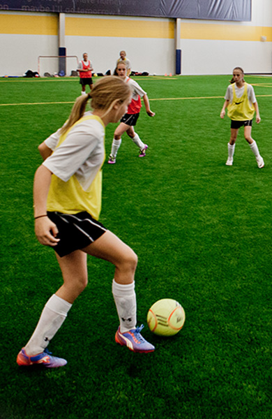 person kicking soccer ball inside Sanford Fieldhouse