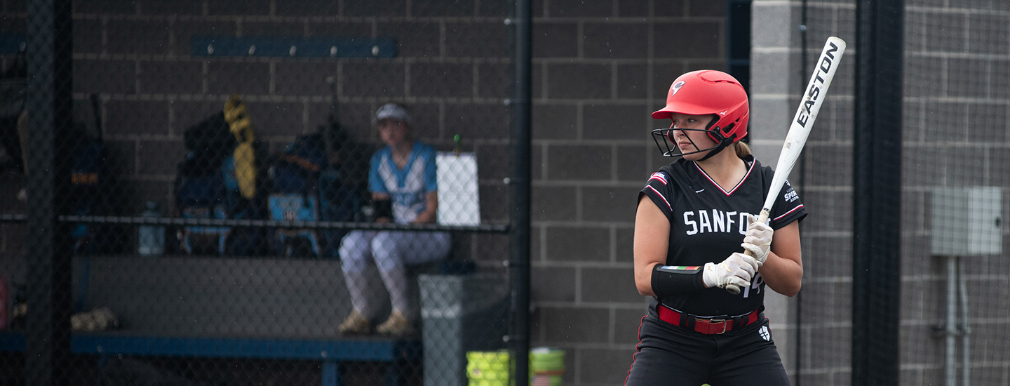 softball player standing at plate with bat waiting for the ball