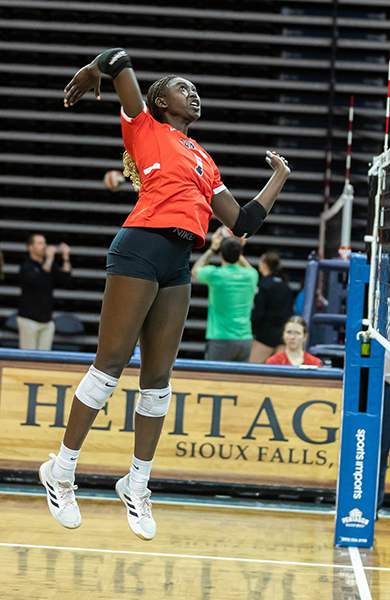 volleyball player in red jersey jumping to spike ball near the net